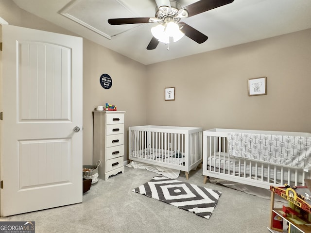 carpeted bedroom with a crib and ceiling fan