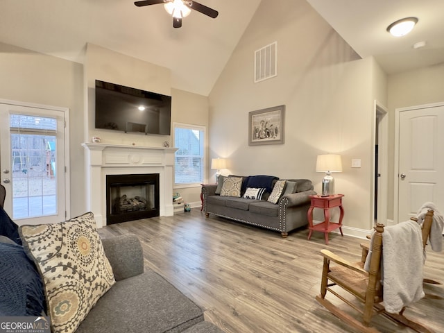 living room featuring ceiling fan, a healthy amount of sunlight, high vaulted ceiling, and light wood-type flooring