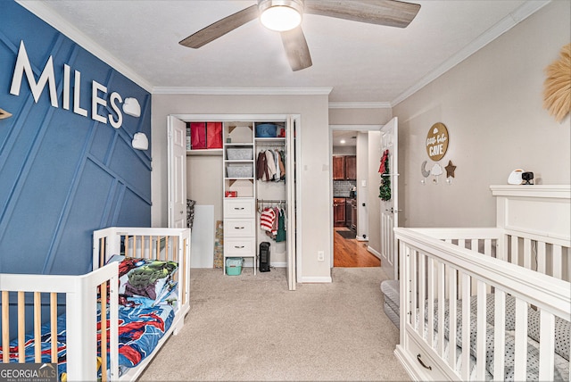 bedroom featuring crown molding, carpet flooring, a closet, a nursery area, and ceiling fan