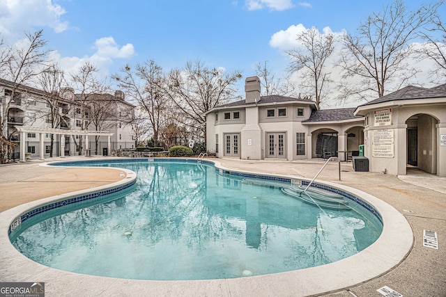 view of swimming pool with french doors and a patio