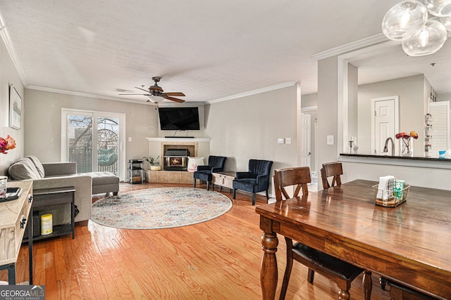 living room featuring hardwood / wood-style floors, a textured ceiling, ornamental molding, and ceiling fan