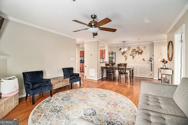 living room featuring hardwood / wood-style flooring, ornamental molding, and ceiling fan with notable chandelier