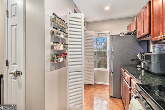 kitchen with electric stove, dark stone counters, and light hardwood / wood-style flooring