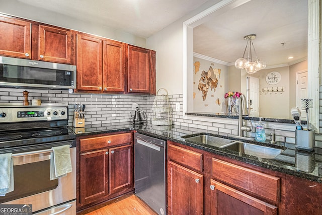 kitchen with pendant lighting, sink, dark stone countertops, backsplash, and stainless steel appliances