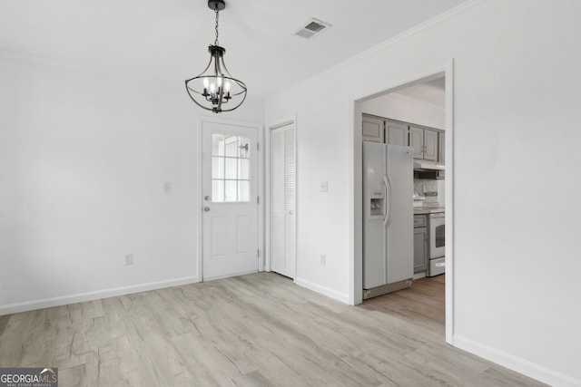 foyer featuring crown molding, a chandelier, and light hardwood / wood-style flooring