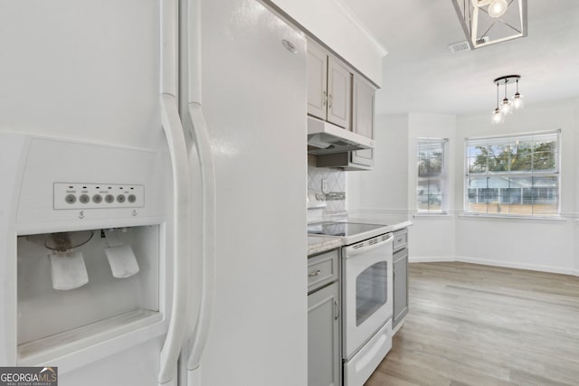 kitchen with light wood-type flooring, gray cabinets, pendant lighting, white appliances, and decorative backsplash