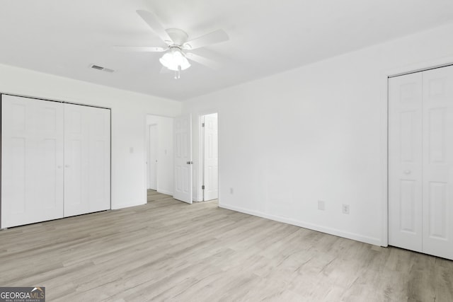 unfurnished bedroom with multiple closets, ceiling fan, and light wood-type flooring