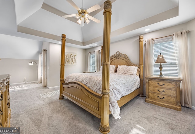 carpeted bedroom with ceiling fan, lofted ceiling, and a tray ceiling