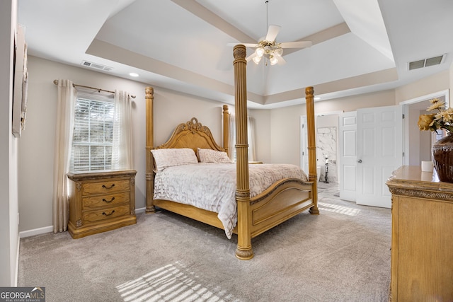 carpeted bedroom with a raised ceiling, ceiling fan, and ensuite bathroom