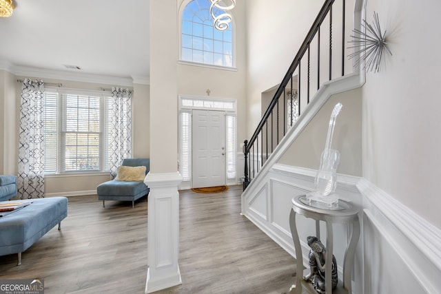 entrance foyer featuring crown molding, decorative columns, and light hardwood / wood-style flooring