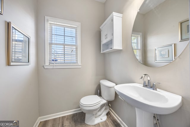 bathroom with wood-type flooring, a healthy amount of sunlight, sink, and toilet