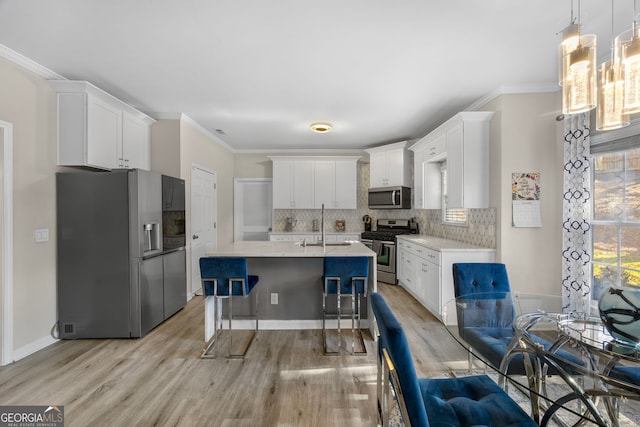 kitchen with tasteful backsplash, sink, white cabinets, hanging light fixtures, and stainless steel appliances