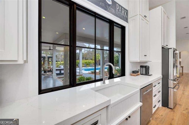 kitchen featuring white cabinetry, appliances with stainless steel finishes, light stone countertops, and sink