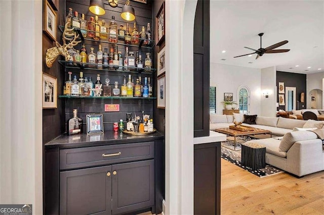 bar with gray cabinets, ceiling fan, and light wood-type flooring