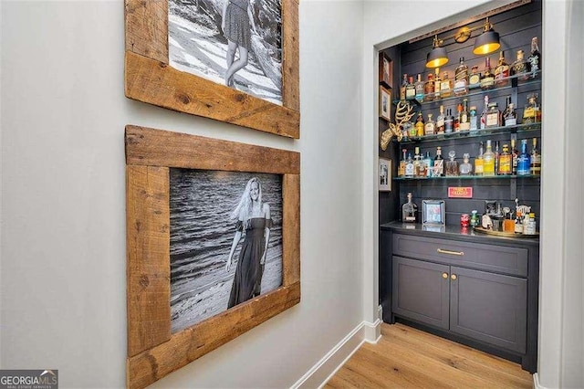 bar featuring gray cabinetry and light hardwood / wood-style floors