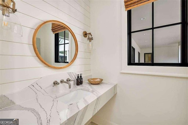 bathroom featuring wooden walls and sink