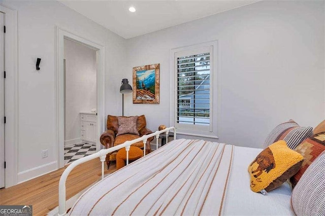 bedroom with hardwood / wood-style floors and ensuite bath