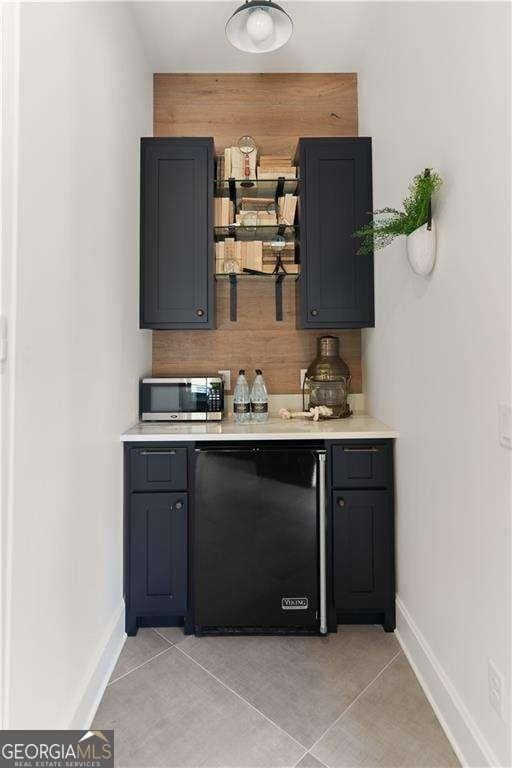 bar featuring fridge and light tile patterned floors