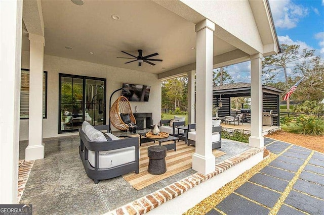 view of patio / terrace with ceiling fan and an outdoor living space with a fireplace