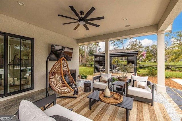 view of patio with a gazebo, ceiling fan, and an outdoor living space with a fireplace