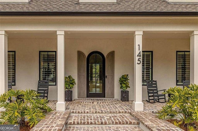 view of exterior entry featuring covered porch