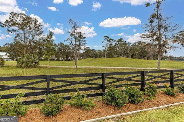 view of gate with a yard and a rural view