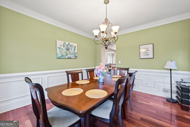 dining room with a notable chandelier, hardwood / wood-style flooring, and ornamental molding