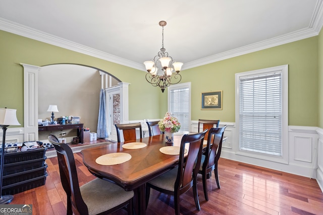 dining area with hardwood / wood-style flooring, ornate columns, ornamental molding, and a notable chandelier