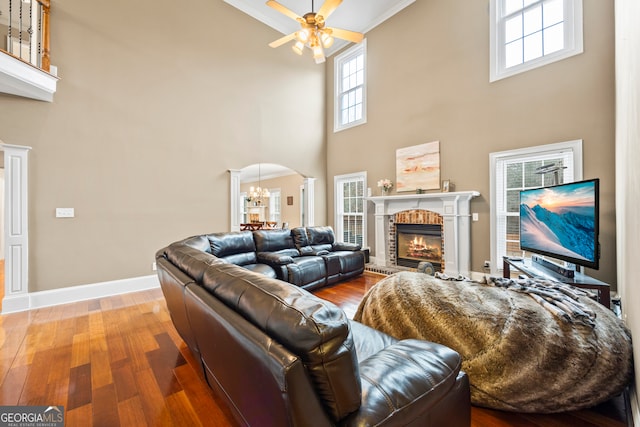 living room featuring hardwood / wood-style floors, a fireplace, ceiling fan, and a high ceiling