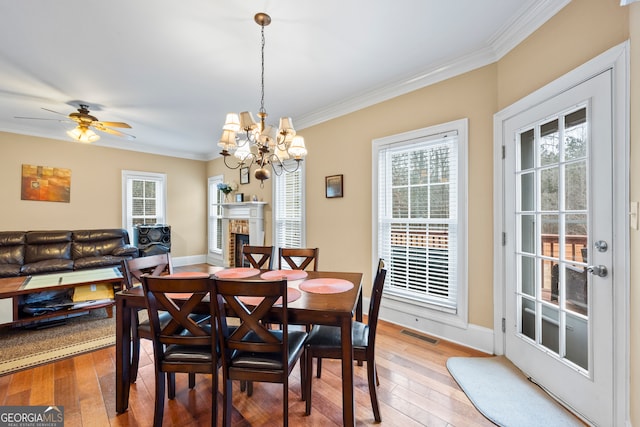 dining space with crown molding, wood-type flooring, ceiling fan with notable chandelier, and plenty of natural light