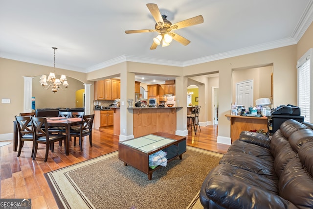 living room featuring ornamental molding, ceiling fan with notable chandelier, and light wood-type flooring