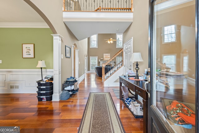 foyer featuring hardwood / wood-style floors, decorative columns, a high ceiling, ceiling fan, and crown molding