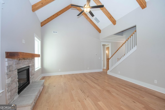 unfurnished living room with ceiling fan, a stone fireplace, light wood-type flooring, and high vaulted ceiling