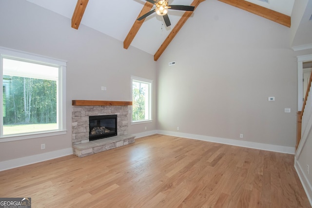 unfurnished living room featuring a stone fireplace, light hardwood / wood-style flooring, high vaulted ceiling, and beamed ceiling