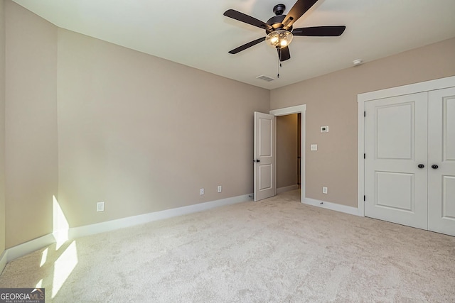 unfurnished bedroom with light carpet, ceiling fan, and a closet