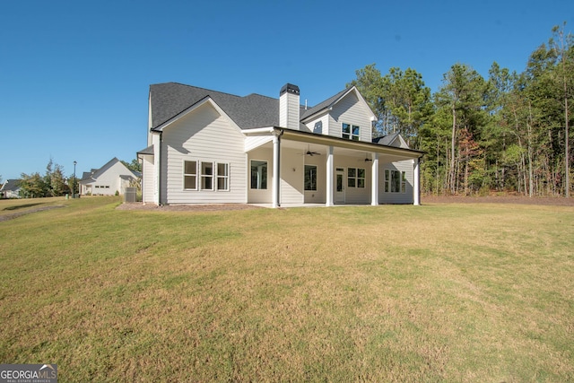 rear view of property with ceiling fan and a lawn