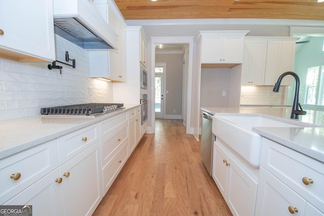 kitchen featuring white cabinetry, decorative backsplash, custom exhaust hood, and appliances with stainless steel finishes