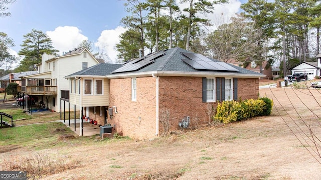 view of side of property with central air condition unit and solar panels