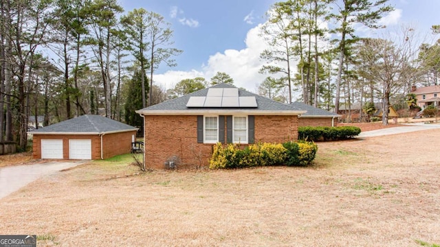 view of home's exterior featuring a garage, an outdoor structure, and solar panels