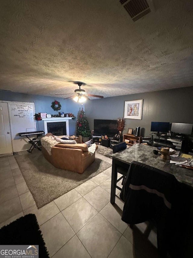 living room with light tile patterned flooring, a textured ceiling, and ceiling fan