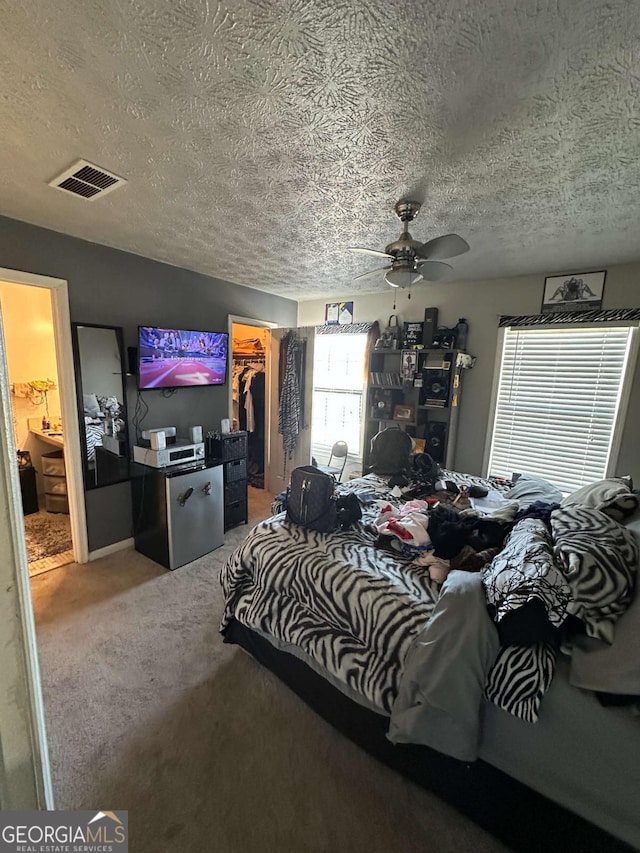 bedroom featuring a walk in closet, carpet floors, a textured ceiling, and a closet