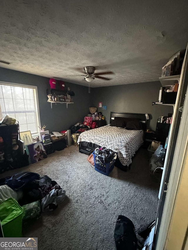 carpeted bedroom featuring ceiling fan and a textured ceiling