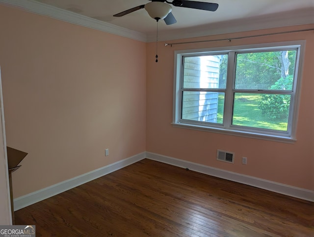 empty room featuring healthy amount of natural light, baseboards, a ceiling fan, dark wood-type flooring, and ornamental molding