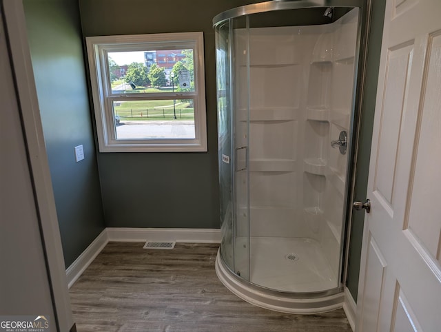 bathroom with a shower stall, wood finished floors, and baseboards