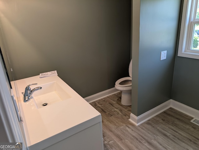 bathroom featuring toilet, wood finished floors, vanity, and baseboards