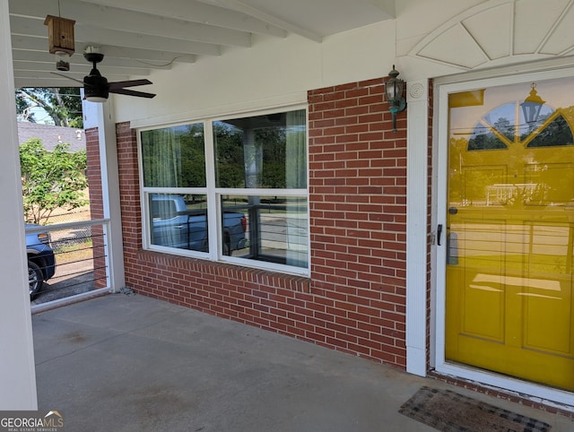 view of exterior entry with brick siding and a ceiling fan
