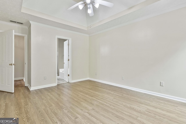 spare room with crown molding, a tray ceiling, light hardwood / wood-style floors, and ceiling fan