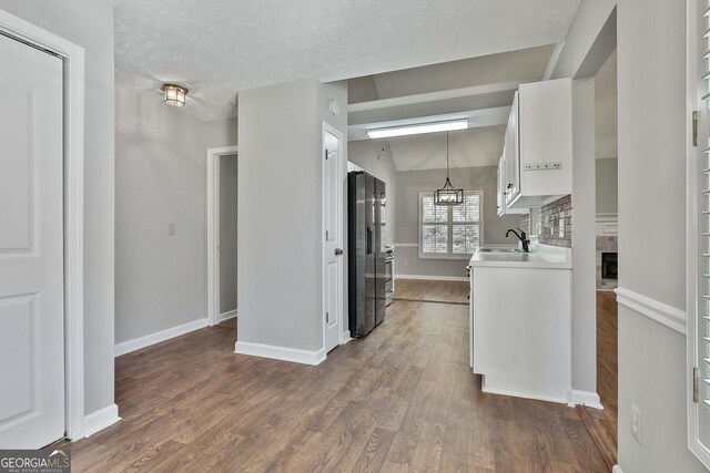 kitchen featuring vaulted ceiling, pendant lighting, white cabinets, stainless steel appliances, and light wood-type flooring