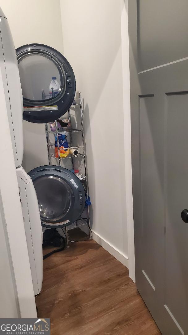 washroom featuring stacked washer and clothes dryer and dark wood-type flooring