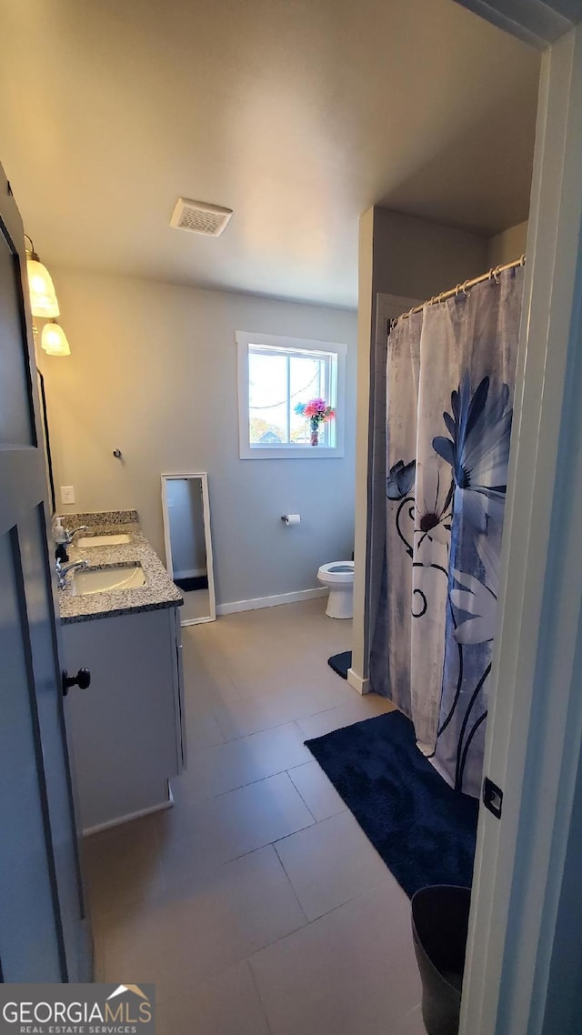 bathroom with tile patterned flooring, vanity, and toilet